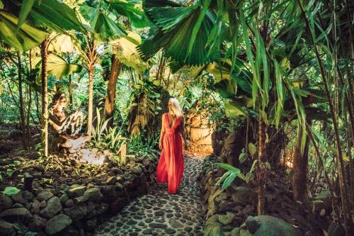 a woman in a red dress walking through a forest at Rohotu Fare in Bora Bora