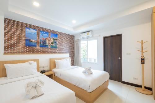 a bedroom with two beds and a brick wall at U Hatyai Hotel in Hat Yai