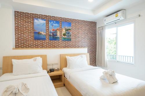 two beds in a room with a brick wall at U Hatyai Hotel in Hat Yai