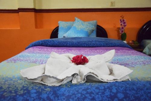 a bed with white towels and a red flower on it at Siddhartha Garden Ayurveda in Pokhara