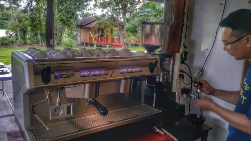 a man is standing next to a coffee machine at Chiang Dao Reset in Chiang Dao