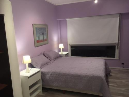 1 dormitorio con paredes moradas y 1 cama con 2 lámparas en ApartFlorida1 en Buenos Aires