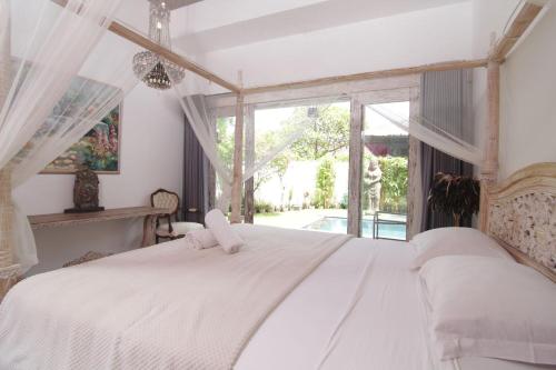 a bedroom with a bed with white sheets and a window at Bamboo Moon Villas in Sanur