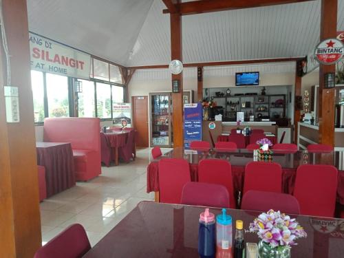 uma sala de jantar com cadeiras vermelhas e mesas num restaurante em Noah Hotel Silangit em Siborongborong