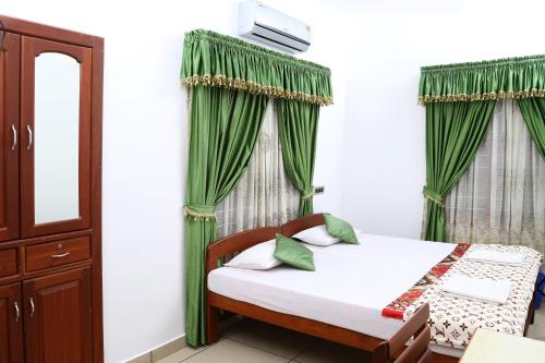 1 dormitorio con 1 cama con cortinas verdes en kevins Placid Homestay, en Kochi