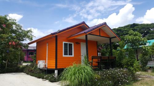 una pequeña casa con un exterior de color naranja en รุ่งฟ้า ฟาร์มสเตย์, en Ban Sap Phrik