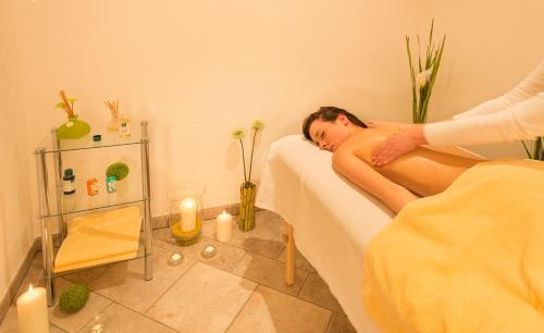 a naked man laying on a bed in a room with candles at Residence Wiesenhof in Vollan
