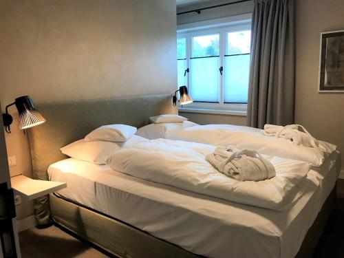 a large white bed in a room with a window at Lerchenhof in Wenningstedt