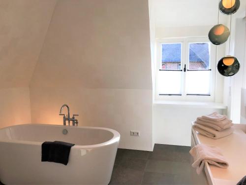 a white bath tub in a bathroom with a window at Lerchenhof in Wenningstedt