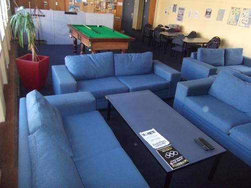 a living room with blue couches and a pool table at Archies Bunker Affordable Accommodation in Napier