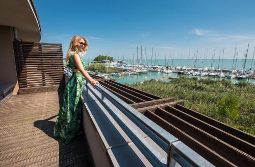 a woman standing on a balcony overlooking a marina at Hotel Golden Lake Resort in Balatonfüred