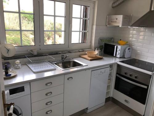 een keuken met een wastafel en een magnetron bij Salty House - Casa Salgada in Foz do Arelho