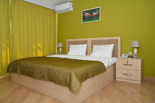 a bedroom with a large bed with green walls at Flamingo Hotel Baku in Baku