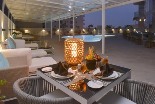 a dining table on a patio with a light fixture at Swiss-Belresidences Juffair in Manama