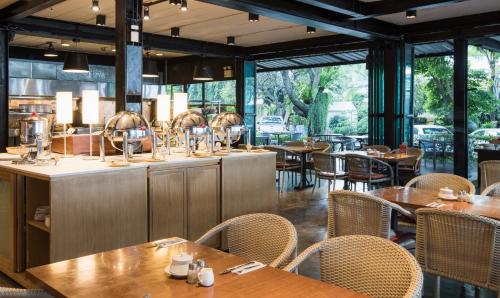 Un restaurante con mesas y sillas de madera y ventanas. en Sandalay Resort, en Pattaya central