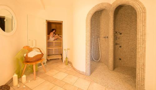 a bathroom with a shower and a woman standing in a doorway at Residence Wiesenhof in Vollan