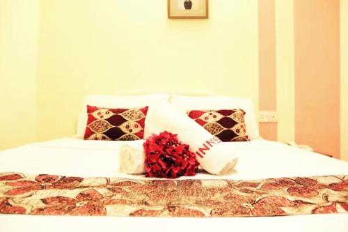 un letto bianco con cuscini e un fiore rosso sopra di Sun Inns Hotel Sunway Mentari a Petaling Jaya
