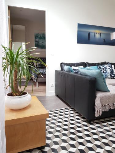 ein Wohnzimmer mit einem Sofa und einer Topfpflanze in der Unterkunft 35m2 - 10 min de CDG - Jeux Olympique 2024 in Le Thillay