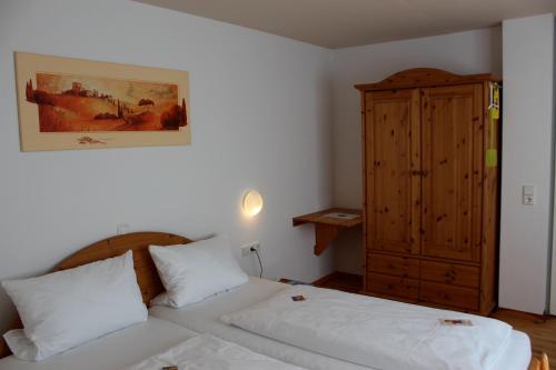 a bedroom with a white bed and a wooden cabinet at Hotel Sunnegässle in Rust