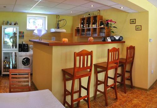 a kitchen with a bar with four wooden stools at Privat Monika in Liptovský Mikuláš