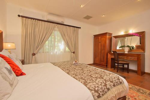 a bedroom with a bed and a desk and a window at Tzaneen Country Lodge in Tzaneen