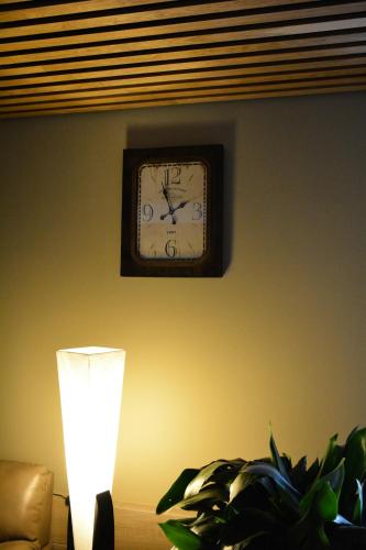 a clock on the wall next to a lamp and a plant at Hotel Garnet Tbilisi in Tbilisi City