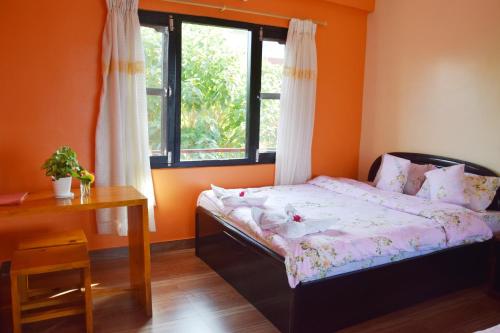 a bedroom with a bed and a desk and a window at Siddhartha Garden Ayurveda in Pokhara