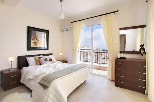 a bedroom with a large bed and a balcony at Club Coral View Resort in Peyia