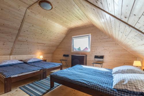 a attic room with two beds and a window at Domki Letniskowe Błękit in Jastrzębia Góra