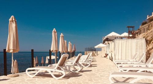 a row of chairs and umbrellas on a beach at Sveti Luka Apartments in Dobra Voda