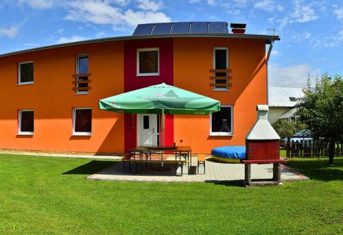an orange building with a table and an umbrella at Privat Monika in Liptovský Mikuláš
