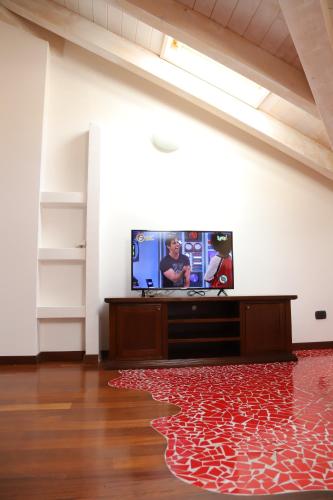 uma sala de estar com uma televisão de ecrã plano e um tapete vermelho em Mansarda Ivy em Finale Ligure