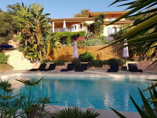 un resort con piscina attrezzata con sedie e ombrelloni di Villa Mimosa a Favone