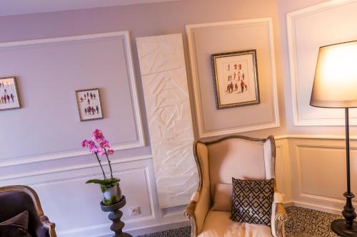 a living room with a chair and a vase of flowers at Hotel Le Lion D'Or et Restaurant La Table Du Lion in Bayeux