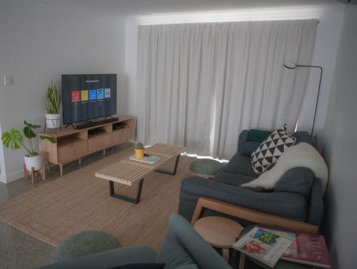 a living room with a blue couch and a tv at FortyTwo - Oceanside Retreat Busselton in Busselton