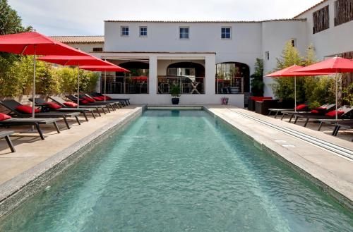 a swimming pool with chairs and umbrellas in front of a building at Vila De La Mar & Spa in Saintes-Maries-de-la-Mer