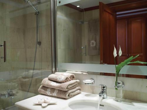 een badkamer met een wastafel, een spiegel en handdoeken bij Serita Beach Hotel in Chersonissos