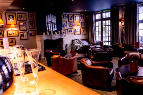a bar with chairs and a table and a fireplace at Hotel Le Lion D'Or et Restaurant La Table Du Lion in Bayeux