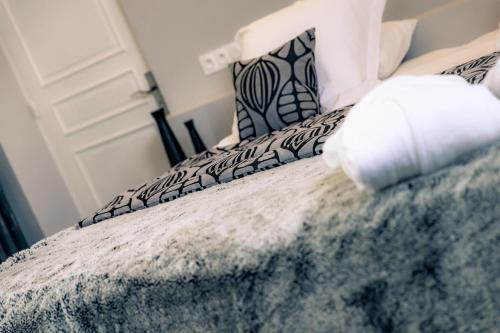 a bedroom with a bed with black and white pillows at Hotel Le Lion D'Or et Restaurant La Table Du Lion in Bayeux