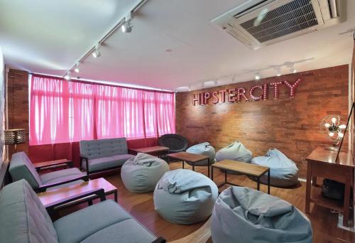 a waiting room with couches and chairs and a sign at hipstercity hostel in Singapore