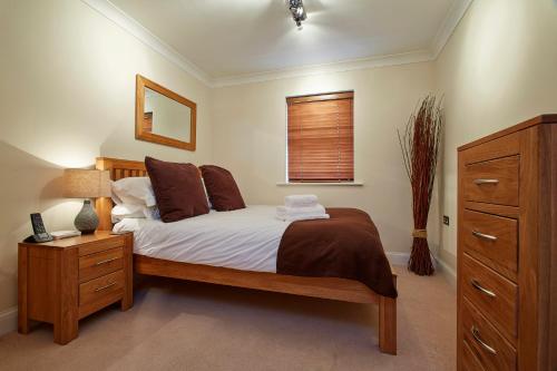 a bedroom with a bed and a dresser and a window at 2 bed 2 bath at Jago Crt in Newbury - FREE parking with no height restrictions in Newbury