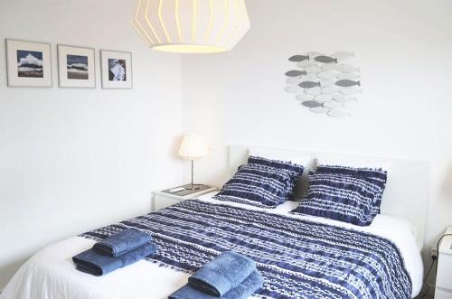 een slaapkamer met een bed met blauwe dekens en kussens bij Silver Breezes Apartment in Nazaré