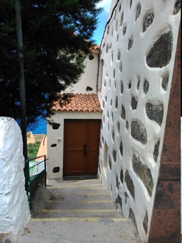 a building with a brown door next to a wall at Histórica Casa de la Oje in Agulo