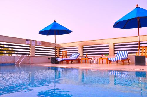 a swimming pool with two chairs and umbrellas next to a pool at Fortune Sector 27 Noida - Member ITC's Hotel Group in Noida