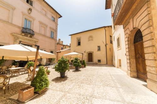 un vicolo in un centro storico con tavoli e ombrelloni di Palazzo Neri a Trevi