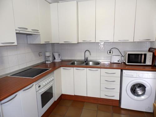 エル・メダノにあるApartamentos Medano - Duplex Maresiaの白いキャビネット、シンク、食器洗い機付きのキッチンが備わります。