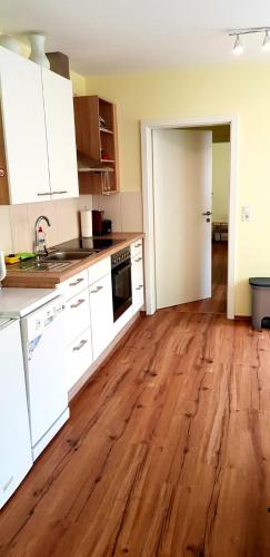 eine leere Küche mit weißen Schränken und Holzböden in der Unterkunft Apartment Hallstadt in Hallstadt