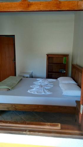 a bedroom with a large bed with white sheets at Chalé da Selma I (Isaías) in Alto Paraíso de Goiás