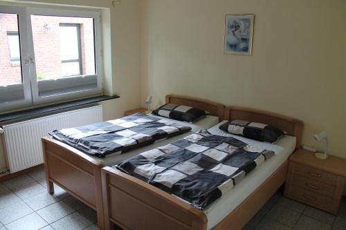 two twin beds in a room with a window at Ferienwohnungen im Gästehaus Sieberns in Carolinensiel