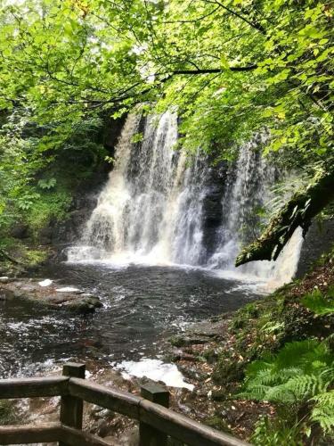 a waterfall in front of a river with a wooden fence at Cullentra House in Cushendall
